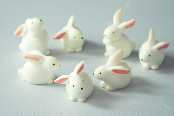 微型白色七兔玩具摆出许多动作在圆圈排在白色的背景图片下载