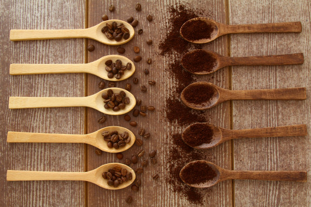 咖啡豆和磨碎的咖啡放在木勺里，棕色的背景图片下载