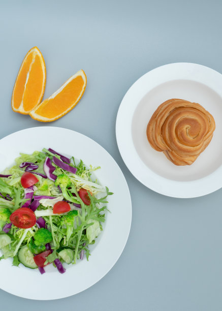 灰色背景上放着一盘健康美味的沙拉和一条面包图片下载