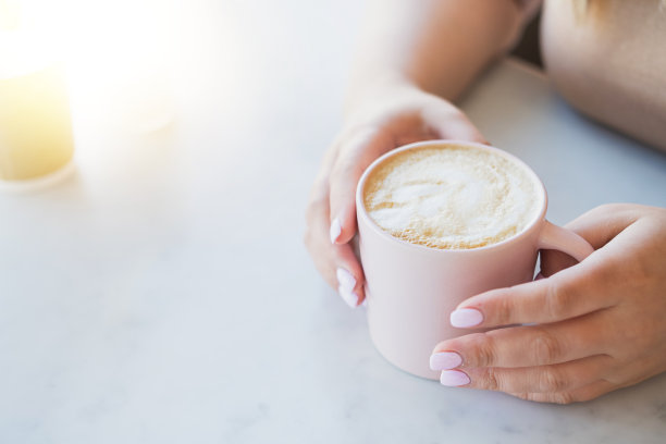 女人的手和一杯热卡布奇诺在桌子上图片下载