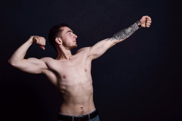一个性感的年轻男子的肖像与肌肉的身体摆姿势在工作室。黑暗的背景。男性的健康。图片下载