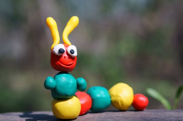 一个用橡皮泥制成的毛毛虫雕像，以野花为背景。图片下载