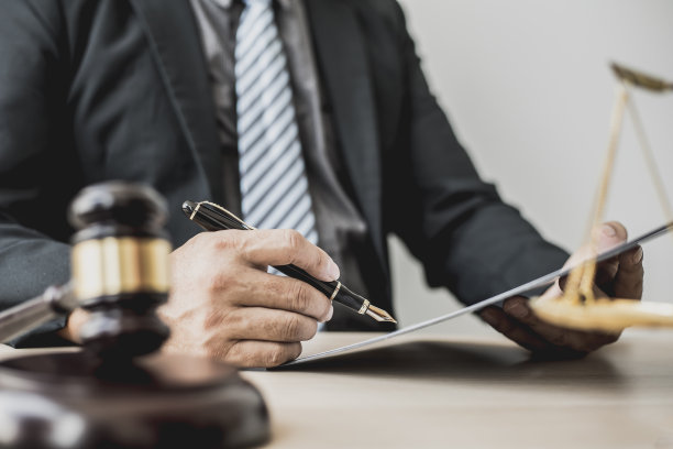 在律师工作的时候，法庭的桌子上有一把小锤子用来敲打法官的桌子。而公正尺度，律师们正在起草一份合同供当事人与被告签署。图片下载