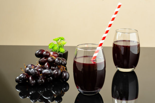用一整杯葡萄汁和一串葡萄在玻璃旁边提供一个反射表面图片下载