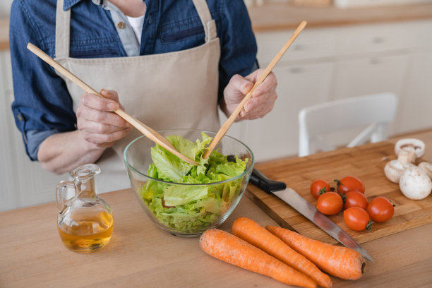 近距离拍摄了一位老年妇女烹饪新鲜蔬菜沙拉的照片，健康饮食，节食。素食和纯素食的概念。在家做饭，准备食物和饭菜图片下载