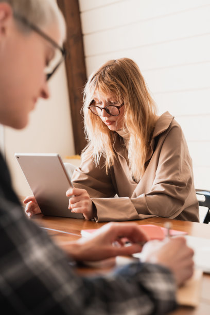 两个忙碌的年轻女学生的垂直图像电子学习，远程在线工作，在宿舍图书馆大学学院做作业。共同办公区域工作。内政部被封锁图片下载