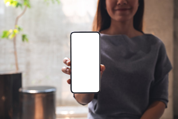 一个漂亮的女人展示一个白色屏幕的手机图片下载