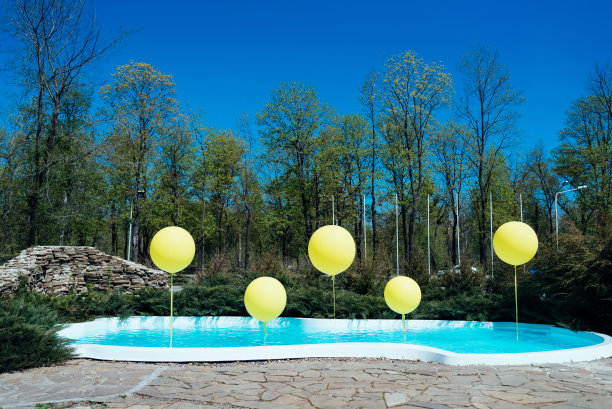 室外有黄色大气球的游泳池。池畔派对。气球在水上。蓝色水池边的婚礼装饰图片下载
