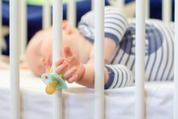 小男孩手里拿着奶嘴假人安静地睡在床上图片下载