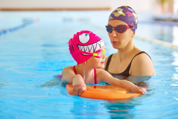 母亲或教练学习游泳的肖像与扑板小女孩在公共游泳池。空间的文本图片下载