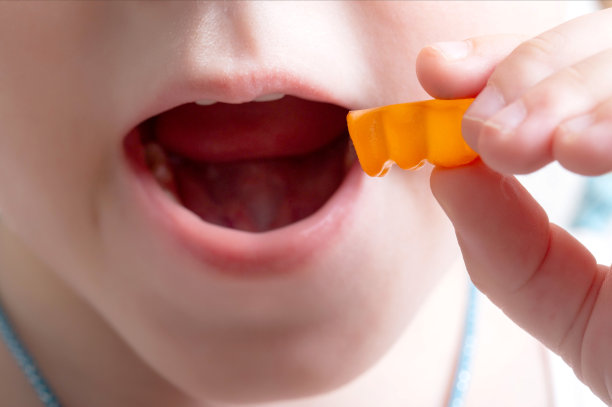 一个小女孩以熊的形式吃了一种维生素。用多种维生素复合物加强儿童健康的概念。特写,美味图片下载