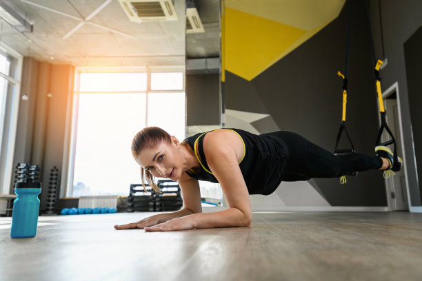 拿着运动器材的女孩看着镜头。中年妇女的手放在地板上，双腿伸直，形成齿轮圈图片下载