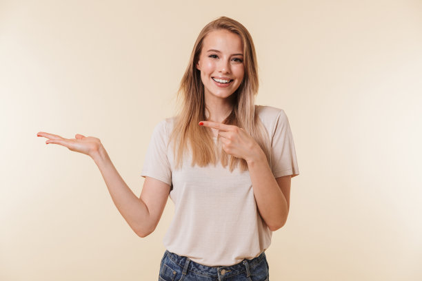 图片特写，一个金发的欧洲女人穿着休闲服装微笑着指着手心，在米色的背景下孤立图片下载