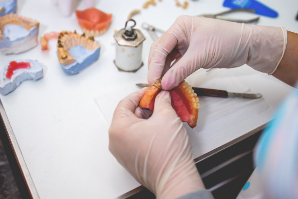 一个牙科技术人员塑造一个修复牙齿的工具在工作桌上的特写。图片下载