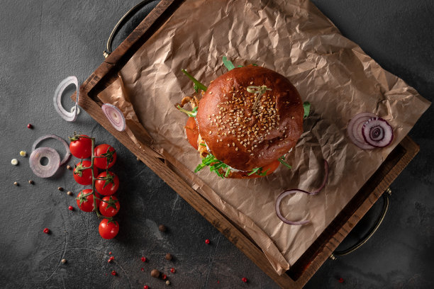 大的美国鸡肉咖喱汉堡在黑色的背景。木盘上的牛排配芝士、番茄、洋葱和芝麻菜，俯视图图片下载