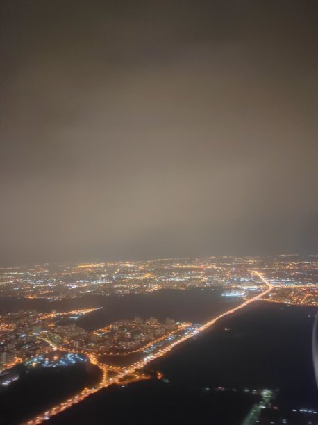 从自然和城市的舷窗观看。俯视图积云和夜晚的城市。图片下载