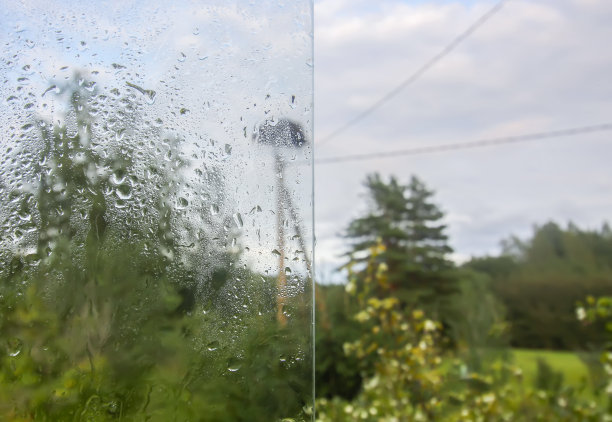 32、鹳巢和绿树后的湿玻璃下着秋雨的雨滴图片下载