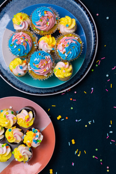 色彩鲜艳的纸杯蛋糕，黑色背景上还撒着糖屑图片下载
