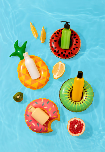 暑假化妆品。防晒乳液，防晒霜，保湿霜。夏日护肤理念。防晒产品的瓶子模型在明亮的背景与水果图片下载