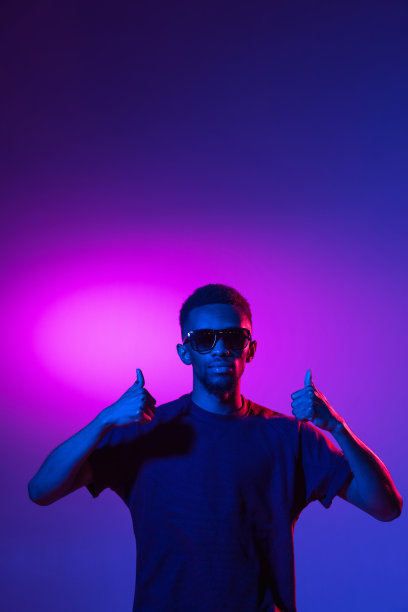 一个非洲裔美国年轻人的肖像，背景是霓虹灯。人的情感、面部表情、青春、销售、广告的概念。图片下载