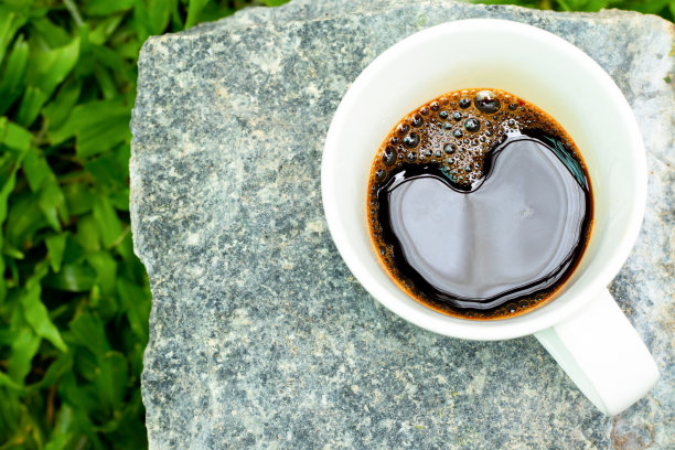 高角度的咖啡在岩石和模糊的绿草背景。图片下载