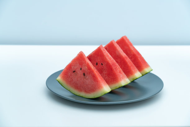 一块西瓜放在一个深蓝色的盘子里。图片下载