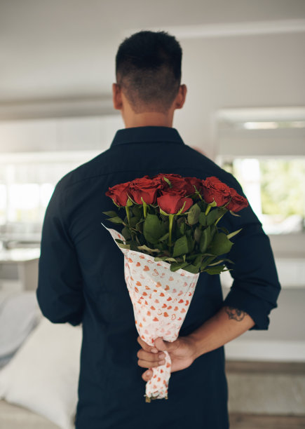 一个年轻人在家里背后拿着花图片下载