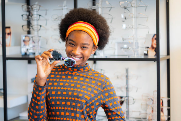 非洲少女拿着新的太阳镜镜框在眼镜店。图片下载