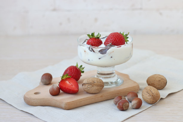 在杯子上放上巧克力和新鲜草莓的冰淇淋。杯装冰淇淋，配草莓、巧克力、核桃、榛子图片下载