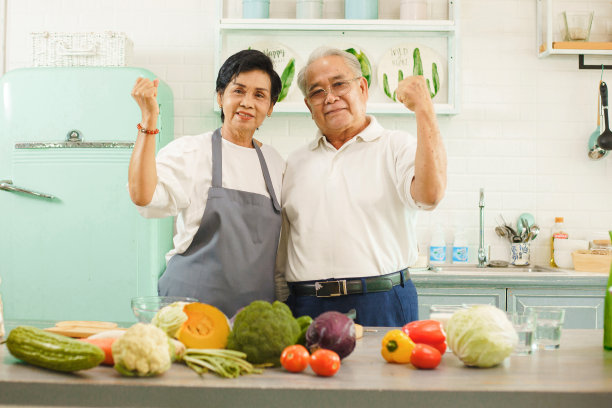 图为一对年老的亚洲夫妇在家里的厨房里做饭。他们有微笑和弯曲的手臂显示力量。退休人员通过选择健康的食物来照顾自己。图片下载
