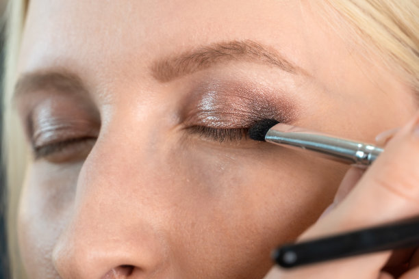 化妆师为一个年轻女子在棕色和粉红色的近距离眼妆图片下载