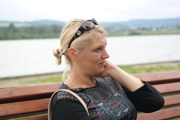 一个年轻女子坐在湖边的公园里，陷入了沉思图片下载