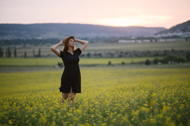 年轻美丽的女子在夏日的黄花田里放松。图片下载