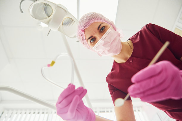 戴防护口罩在口腔诊所工作的年轻女牙医。第一个人的观点图片下载