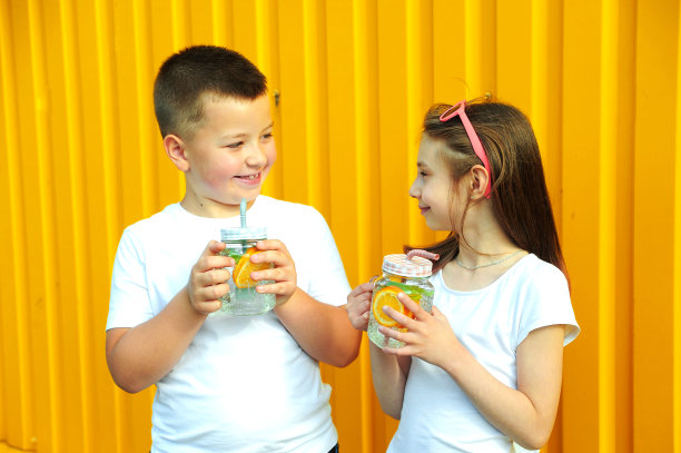 穿着白色t恤的小朋友们拿着橙色和薄荷色的夏日鸡尾酒图片下载