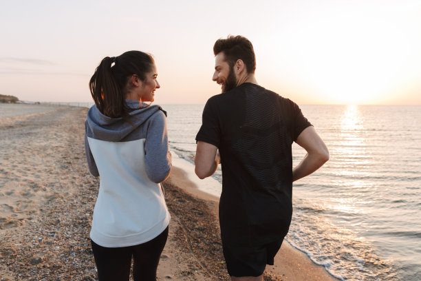 一对年轻夫妇一起在海滩上慢跑的后视图图片下载