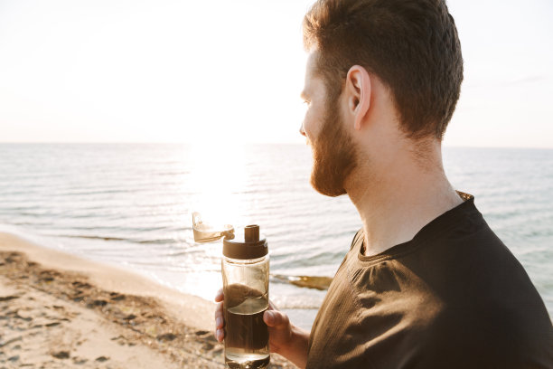 年轻运动员拿着水瓶的侧面图图片下载