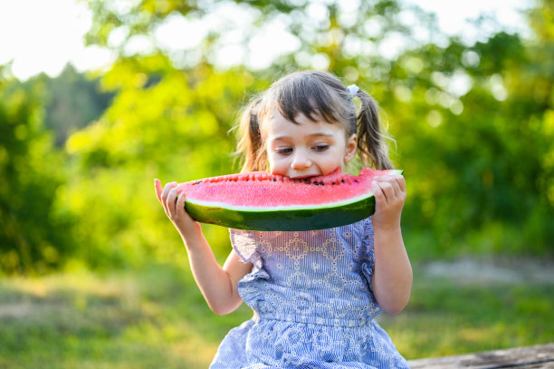 小可爱的白人女孩在花园里吃西瓜图片下载