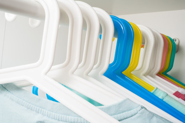 许多彩色的衣架挂在一根杆子上，在衣柜的白色背景上。店面概念、销售、设计、空衣架。图片下载