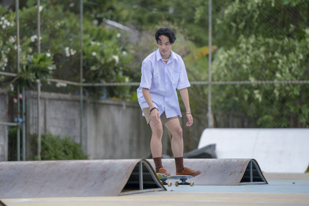 十几岁的亚洲滑板男孩在学生制服滑冰在当地的滑板公园。图片下载