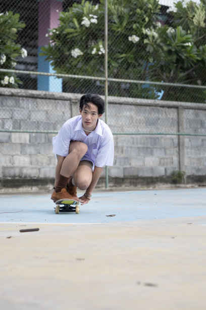 十几岁的亚洲滑板男孩在学生制服滑冰在当地的滑板公园。图片下载