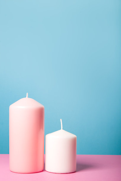 两支粉白色的蜡烛，在蓝色和紫色的背景上图片下载