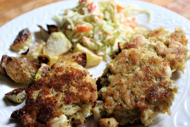 免费照片-近距离观看美味的蟹饼餐-海鲜晚餐包括三个蟹饼，烤帕尔马甘蓝和新鲜切脆的卷心菜-厨师的周五晚上海鲜特餐-最好的蟹饼在汤-晚餐时间的最爱图片下载