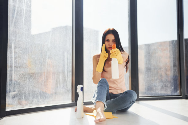 一个女人的肖像坐在窗台上，手里拿着一瓶清洁喷雾图片下载