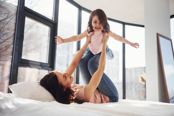 年轻的母亲和她的女儿玩在床上的周末时间一起图片下载