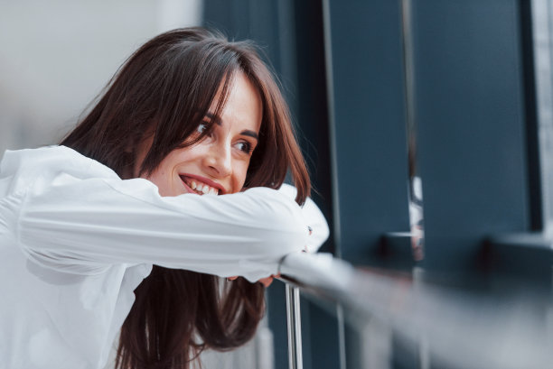 画像的褐发在室内白色衬衫，倚在室内的栏杆图片下载