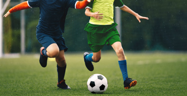 足球运动员在雨中决斗。年轻的足球运动员与球决斗图片下载
