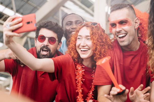 年轻的一群快乐的多民族朋友在足球场有乐趣-兴奋的体育迷在他们的球队在足球比赛胜利后自拍图片下载