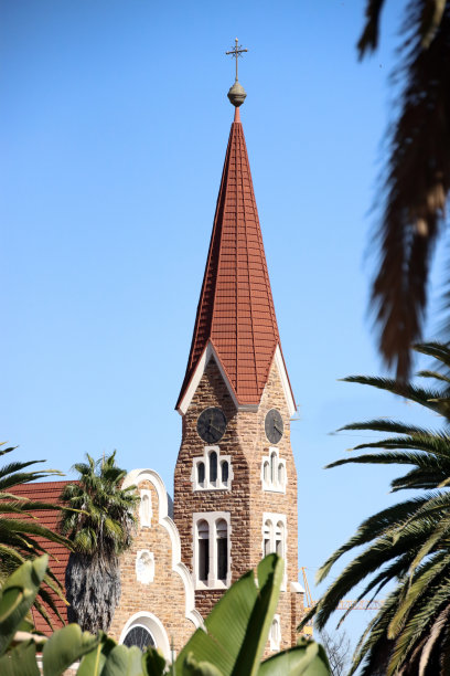纳米比亚温得和克教堂的特写，蓝色的天空在背景和绿色的棕榈叶在前景。图片下载