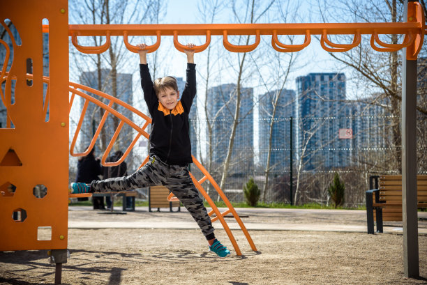 可爱的男孩正在校园操场上爬。他有一张非常快乐的脸，喜欢独自在户外进行这种冒险运动。温暖的阳光明媚的日子图片下载